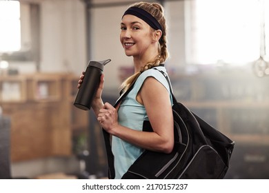 Im ready for my gym session. Shot of a young woman holding a water bottle and carrying her gym bag. - Powered by Shutterstock