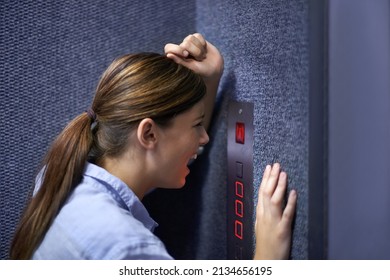 Im stuck in here. Shot of a fearful woman shouting into an elevator intercom.