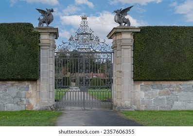 Imaculate hedges with an ornate iron gate and gate posts topped with dragons