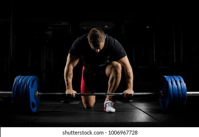 Professionele atleet boog zich over de halter en bereidt zich voor om een ​​zeer zwaar gewicht op te tillen. Vooraanzicht