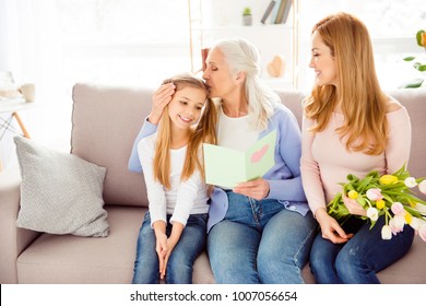 Motherhood parenthood relationship comfort people holiday festive concept. Cute friendly family gathering on birthday excited granny kissing sweet girl's head mommy with fresh beautiful flowers