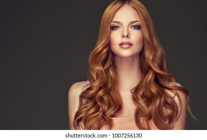 ツヤツヤの長いウェーブのかかった髪をした赤毛の少女。巻き毛のヘアスタイルを持つ美しいモデルの女性。