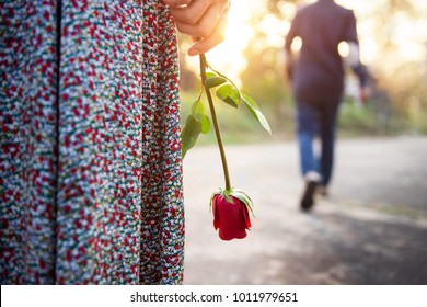Kesedihan Cinta dalam Mengakhiri Konsep Hubungan, Wanita Patah Hati Berdiri dengan Mawar Merah di Tangan, Pria Kabur di Sisi Belakang Berjalan sebagai latar belakang