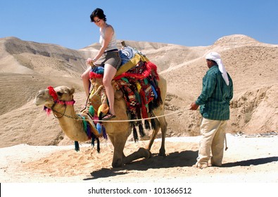 Du khách cưỡi lạc đà của một người đàn ông Bedouin ở sa mạc Judaean, Israel. Người thật. Sao chép không gian