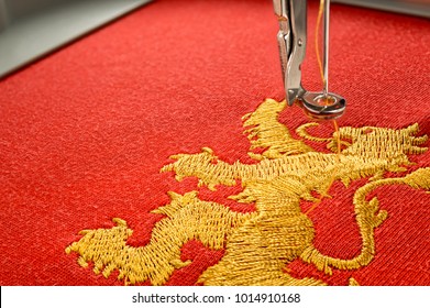 Close-up foto borduurwerk ontwerp gouden leeuw op rode stof borduur machinaal, kopieer ruimte aan de linkerkant.