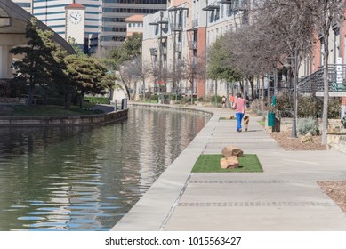 Vista posterior de personas no identificadas corriendo, paseando a un perro a lo largo del canal Mandalay en Irving, Texas, EE.