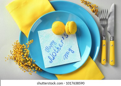 Tischdekoration mit Karte zum Muttertagsbrunch auf hellem Hintergrund