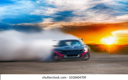 Kabur dari mobil drift ras difusi gambar dengan banyak asap dari ban yang terbakar di jalur cepat saat matahari terbenam.