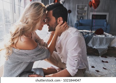 Loving everything about her. Beautiful young couple bonding and smiling while sitting in the bedroom