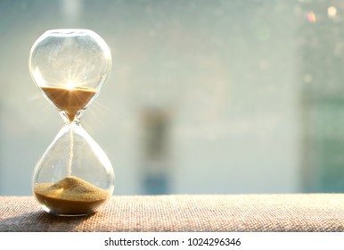 Concepto de paso del tiempo de vida. Reloj de arena con fondo de luz solar