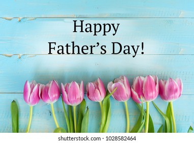 Rosa Tulpen auf einem blauen Planken-Hintergrund mit glücklichem Vatertags-Zitat. Vatertagskarte