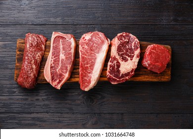 Variedad de filetes de carne cruda Black Angus Prime Machete, Blade on bone, Striploin, Rib eye, Tenderloin fillet mignon en tablero de madera