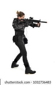 Porträt in voller Länge des weiblichen Soldaten, der schwarze taktische Rüstung hält, die eine Waffe hält, lokalisiert auf weißem Studiohintergrund.