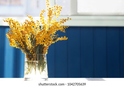 春の黄色いミモザの花。窓の背景に、テーブルのクローズアップのガラスの花瓶にアカシアdealbata、銀の編み枝細工またはミモザ。花の春の背景、3月8日、イースター。太陽光線、バックライト