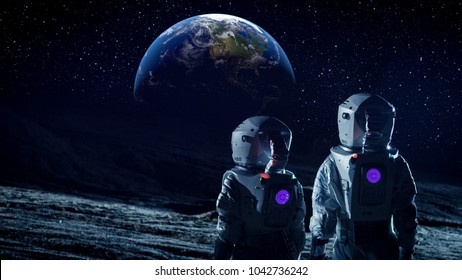 Dos astronautas en trajes espaciales parados en la luna y miran la hermosa tierra en el cielo. Viajes espaciales, mundo habitable y concepto de colonización.