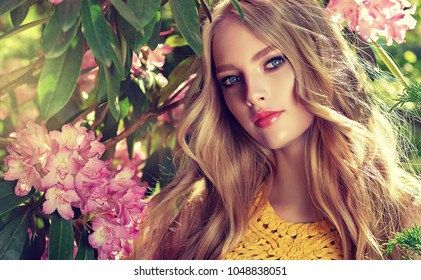 Schéint Fréijoers Meedchen a parfüméierter rosa Blummen am Summer Blossom Park. Fra an engem bléien Gaart. Moud, Kosmetik a Parfumen. Curly blond Hoer