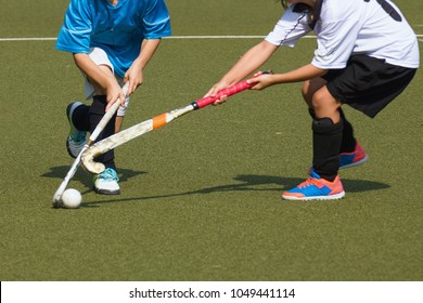 Two child field hockey players. Attacker in blue jersey dekes defender in white and gets past her or him