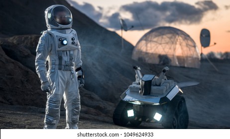 Astronaut in Space Suit Confidently Standing on Alien Planet, Exploration of the the Planet's Surface. In the Background Research Base/ Station and Rover. Space Travel, Colonization Concept.