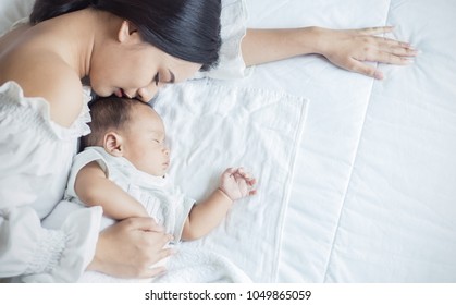 Tutup potret gadis muda kaukasia muda yang cantik mencium bayinya yang baru lahir yang sehat tidur di tempat tidur dengan ruang fotokopi Perawatan kesehatan dan cinta medis konsep hari ibu gaya hidup wanita asia