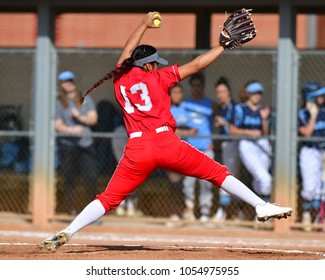 Girl winding up and throwing a fastball for a strike during a softball game