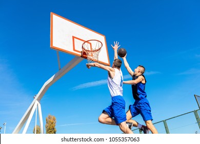 Joven jugador callejero de baloncesto haciendo slam dunk