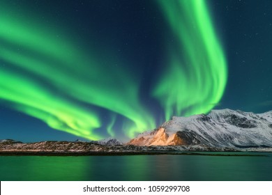 Nordlicht. Lofoten-Inseln, Norwegen. Aurora. Grüne Nordlichter. Sternenhimmel mit Polarlichtern. Nachtwinterlandschaft mit Aurora, Meer mit Himmelsreflexion und schneebedeckten Bergen. Natur. Reisen