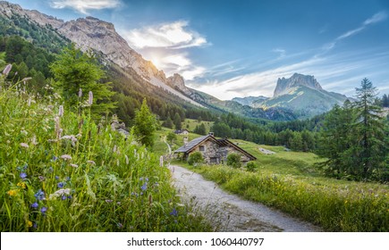 春、南チロル、イタリアの青い空と雲のある晴れた日に、伝統的な古い山のシャレーと新鮮な緑の牧草地を持つ牧歌的なアルプスの山の風景の美しい景色