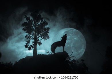 暗いトーンの霧の背景と満月に対して遠吠えするオオカミのシルエット、または満月に遠吠えするシルエットのオオカミ。ハロウィーン ホラーのコンセプトです。セレクティブ フォーカス