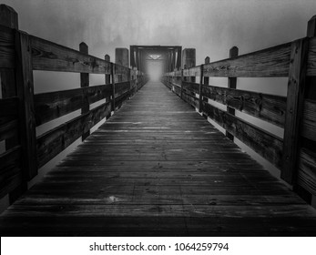 Una inquietante imagen en blanco y negro de una vieja pasarela de celosía sobre el lago en una mañana brumosa en Tims Ford State Park en Winchester Tennessee. Se asemeja a un portal en una película de ciencia ficción.