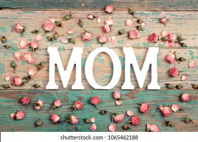 Muttertagshintergrund mit Buchstaben und kleinen rosa Rosen auf altem Holztisch. Glückliches Muttertagskonzept.