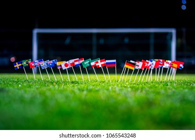 Football ball on green grass and all national flags 
