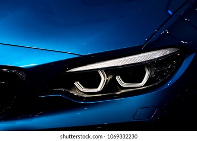 Gros plan d'un phare sur un arrière-plan de voiture de luxe bleue. Concept de voiture de sport moderne et coûteuse