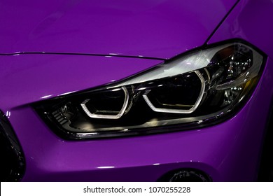 Primer plano de faro en fondo de coche violeta de lujo. Concepto de coche deportivo moderno y caro