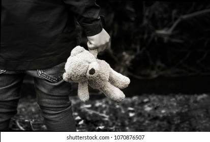 Schwarzweiss-Foto des Kindes, das Teddy hält, der allein im Wald erwacht, Rückansicht eines Jungen, der allein steht und sein Ted, verwöhntes Kind, verlorene Kinder oder obdachloses Kinderkonzept hält
