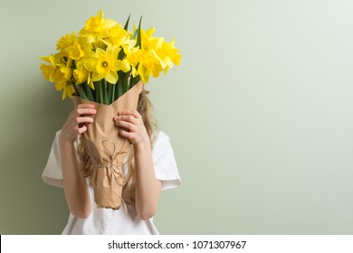 Child girl holding bouquet of yellow flowers.