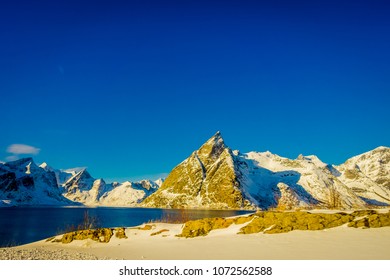 レーヌ、ロフォーテン諸島、ノルウェーの Olenilsoya の豪華な青い空で冬の間に雪で覆われた山頂の屋外ビュー