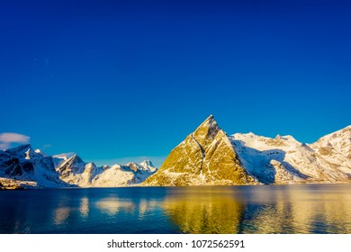 Outdoor view of mountain peaks covered with snow during winter in gorgeous blue sky Olenilsoya in Reine, Lofoten Islands, Norway