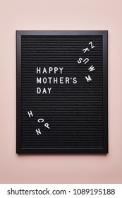 Schwarzes Letterboard mit weißen Kunststoffbuchstaben mit Zitat Happy Mother's Day, auf rosa Hintergrund.