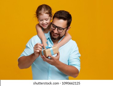 happy father's day! cute dad and daughter hugging on colored yellow background