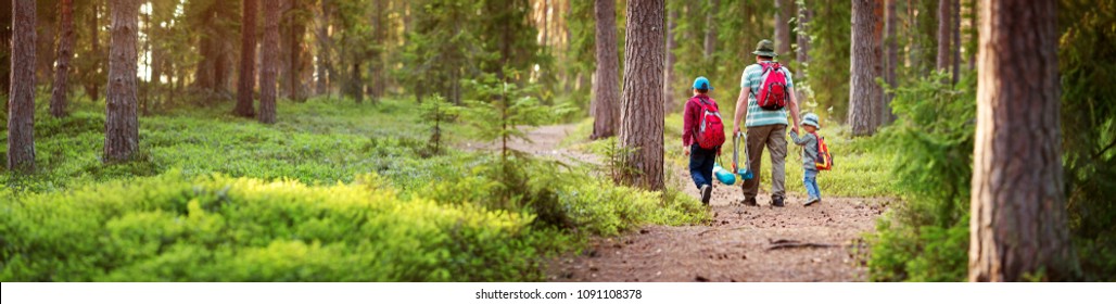 Father and boys going camping with tent in nature. Man with sons with backpacks walking in the forest