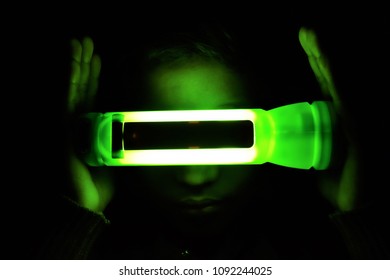 A child intrigued by green light coming from a translucent torch.