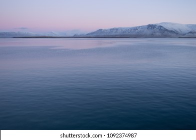 Kalm water met besneeuwde bergen net voor zonsopgang - Haven van Reykjavík, IJsland