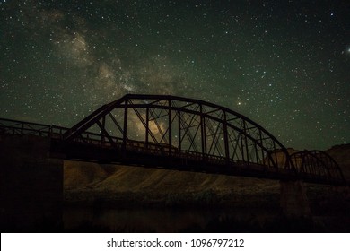 Milky way galaxy night sky with old iron railroad bridge. 