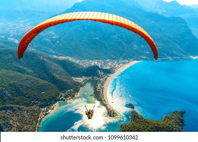 Gleitschirmfliegen am Himmel. Paraglider Tandem fliegt über das Meer mit blauem Wasser und Bergen an einem hellen sonnigen Tag. Luftaufnahme des Gleitschirms und der blauen Lagune in Oludeniz, Türkei. Extremsport. Landschaft