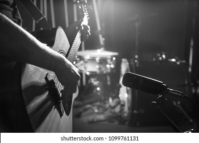 スタジオ マイクは、レコーディング スタジオまたはコンサート ホールでアコースティック ギターのクローズアップを記録し、アウト フォーカス モードで背景にドラム セットを設定します。色付きの提灯の美しい背景をぼかした写真