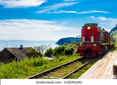 Zomerlandschap met de komst van een rode trein op een houten leeg platform Trans-Siberische spoorlijn in dorp aan de oever van het Baikalmeer. Trein Matanja. Perfecte toeristische achtergrond voor reizen en avontuur