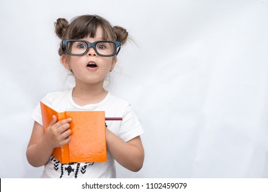 Überraschtes süßes Kind in Brille, mit Bleistift in Notizbuch schreibend, Mund weit offen haltend. Vier oder fünf Jahre altes Kind, isoliert auf Weiß, Platz für Werbetext