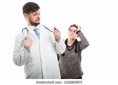 Älterer Patient schaut männlichen Arzt an und blickt seltsam auf Stethoskop isoliert auf weißem Hintergrund