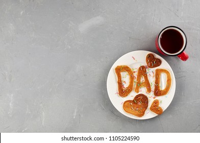 Special Father's Day breakfast. Alphabet Pancakes with sprinkles on white round plate and cup of tea. Top view, copy space on a gray concrete background