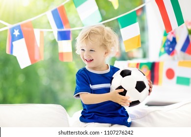Kind kijken naar voetbalwedstrijd op tv. Kleine jongen in Frankrijk tricot kijken naar voetbalwedstrijd tijdens het kampioenschap. Kid fan juichen en ondersteunen van het nationale team. Jonge voetballer met bal voor wedstrijd.